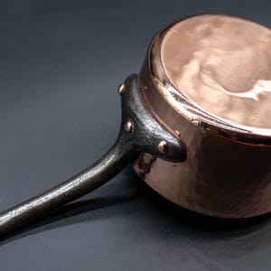 May include: A white ceramic mug with a black handle and the text "But First, Coffee" in a black, handwritten-style font. The mug is on a white surface.