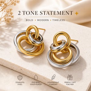 May include: Two-tone statement earrings with interlocking circles in gold and silver. The earrings are made of stainless steel and are PVD real gold plated. The text on the image says "2 TONE STATEMENT" and "BOLD • MODERN • TIMELESS."