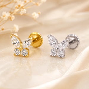 May include: Two butterfly-shaped stud earrings with flat back posts. One earring is gold-toned with clear marquise and round-cut stones forming wings. The other earring is silver-toned with identical clear marquise and round-cut stone settings.