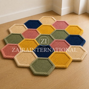 May include: A tufted rug composed of multiple hexagonal segments in shades of navy blue, mustard yellow, sage green, dusty pink, and beige. The rug features a central circular logo with the text ZI and the word ZAIRINTERNATIONAL printed across it.