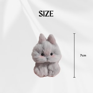 May include: A plush, gray bunny figurine with pink cheeks and small black eyes. The bunny is 7 cm tall. The word "SIZE" is above the bunny.