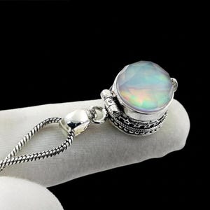 May include: A silver pendant necklace featuring a faceted, iridescent gemstone. The gemstone is set in a detailed, ornate silver setting. The necklace chain is a delicate, textured silver. The overall design is elegant and eye-catching.