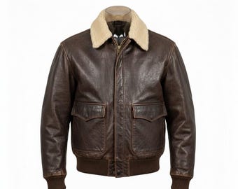 May include: A brown leather bomber jacket with a cream-colored shearling collar. The jacket features two front pockets, a ribbed hem, and cuffs. The jacket is displayed on a mannequin against a white background.
