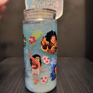 Puede incluir: Un tarro de cristal transparente con tapa, lleno de l&iacute;quido azul y purpurina. El tarro est&aacute; decorado con personajes de dibujos animados y flores rosas. Una pegatina circular en la parte superior dice "Ashley's Beautiful Custom".