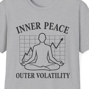 May include: A gray t-shirt with a crew neck featuring the text "INNER PEACE" above a graphic of a person meditating in a yoga pose, with a stock market graph, and the text "OUTER VOLATILITY" below.