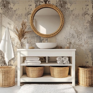 May include: A bathroom vanity with a white countertop, a round mirror with a rope-like frame, and a white sink. The vanity has shelves with folded white towels, woven baskets, and a white rug. The background is a textured wall.