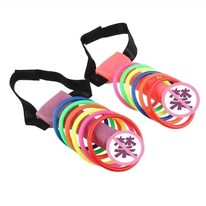May include: Two sex toys with a variety of colorful rings and a black strap. The toys have a pink base and a series of colorful rings in red, orange, yellow, green, blue, and purple. Each toy has a pink circle with a Japanese symbol.