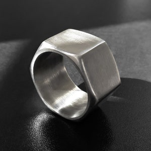 May include: A silver hexagonal ring with a brushed finish.