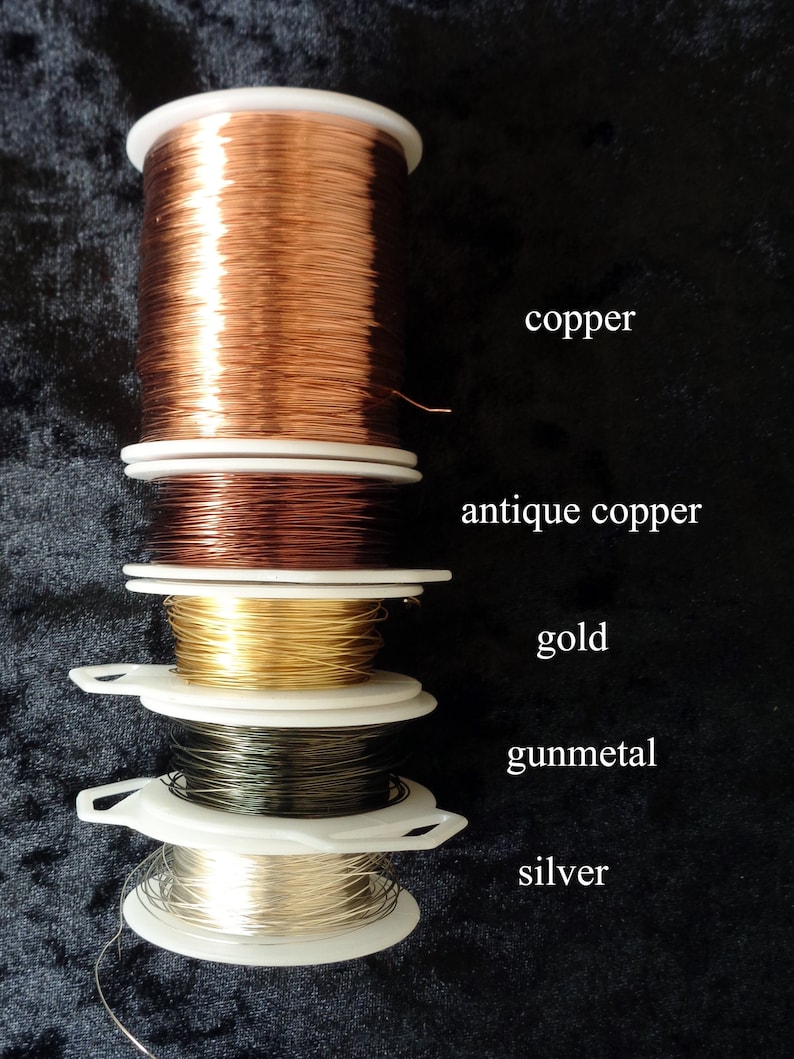 May include: Five spools of wire in different colors: copper, antique copper, gold, gunmetal, and silver. The spools are stacked on top of each other.