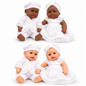 Puede incluir: Cuatro muñecos bebés vestidos con conjuntos de tela blanca bordada. Dos muñecos tienen tonos de piel oscuros y dos tienen tonos de piel claros. Cada par incluye un muñeco con chaqueta de cuello y gorro, y otro con vestido y pañuelo.