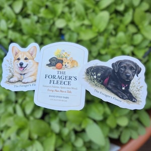May include: Three decorative tags featuring dog illustrations and the text "The Forager's Fleece." One tag shows a corgi, another a black lab puppy, and the third displays a corgi and black lab with text about hand-dyed yarn.