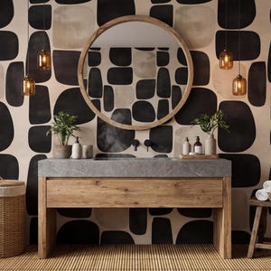 May include: A modern bathroom with a wooden vanity, a round mirror, and a patterned wallpaper in black and beige. The vanity has a gray countertop and a wooden base. A woven hamper and a small wooden stool are also present.
