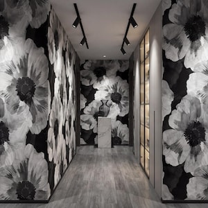 May include: A hallway with floral wallpaper in black and white. The walls are covered in large, stylized flower patterns. The floor is a light gray wood. Track lighting illuminates the space. A decorative vase sits on a marble pedestal.