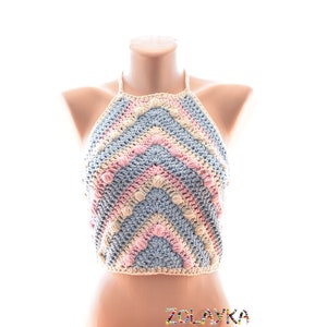May include: A handmade crochet halter top in a chevron pattern. The top features alternating rows of light blue, pink, and cream-colored yarn. The halter top is displayed on a mannequin. The text "ZOLAYKA" is visible at the bottom.