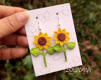 May include: Crocheted sunflower earrings with green leaves and silver hooks. The earrings are displayed on a white card with the text "ZOLAYKA knitting and crochet with love".
