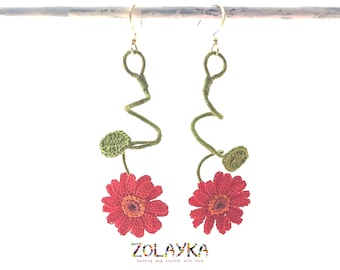 May include: Crocheted earrings with a red flower and green stem. The earrings are hanging from gold hooks.