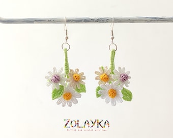 May include: Crocheted daisy earrings with green stems and white, yellow, and pink flowers. The earrings are hanging from silver hooks.