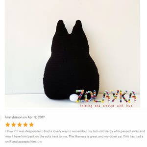 K&ouml;nnte beinhalten: Ein schwarzes geh&auml;keltes Katzenkissen mit dem Namen "ZOLAYKA", der in bunten Perlen geschrieben ist. Der Text "knitting and crochet with love" befindet sich unter dem Namen.