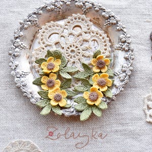 Artisan crochet earrings in buttercup flower design, photographed to show texture and handmade details.