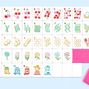 Pu&ograve; includere: Un set di tessere Mahjong bianche con illustrazioni colorate di ciliegie, asparagi, pane, fiori e barattoli di marmellata. Il set include due tessere rosa e una gomma rosa. La parola "JOKER" &egrave; stampata su due tessere.