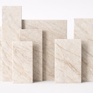 May include: An assortment of rectangular stone tiles in different sizes. The tiles feature a beige and tan marble-effect pattern with delicate veining. The arrangement suggests a display of building materials or decorative elements.