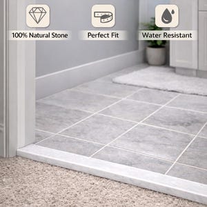 May include: A bathroom doorway featuring a premium marble threshold. The threshold is white and rectangular, contrasting with the gray tiled floor and beige carpet. Text on the image reads "Elevate Your Bathroom!" and highlights features like "100% Natural Stone" and "Water Resistant."