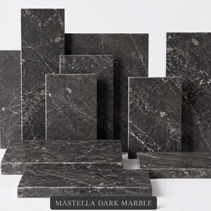 Op de afbeelding: Een verzameling rechthoekige donkergrijze marmeren platen met witte aders, gerangschikt in een gelaagde opstelling. De tekst Mastella Dark Marble staat in het wit gedrukt op een zwart rechthoekig label onderaan in het midden.