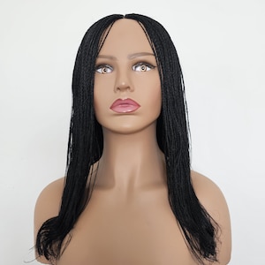 May include: A mannequin head with a black braided wig. The wig features long, thin braids that cascade down the shoulders. The mannequin has a tan complexion, with painted facial features including brown eyes and pink lips. The background is plain white.