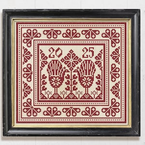 May include: Framed cross-stitch artwork with a cream background and a red floral design. The design includes the numbers "20" and "25", along with stylized floral and heart motifs. The frame is black with a gold inner edge.