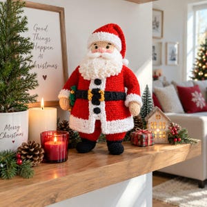 May include: A crocheted Santa Claus doll featuring a red coat with white trim, a black belt with a gold buckle, and a thick white beard. The figure wears a matching red hat with a white brim and black boots, standing upright with a cheerful expression.