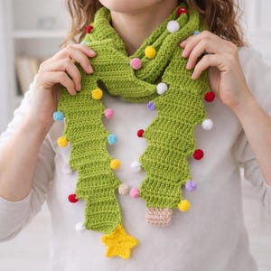 May include: A green crocheted scarf shaped like a Christmas tree, adorned with colorful pom-poms and a yellow star. The scarf is handmade and features a textured stitch pattern, perfect for holiday wear.