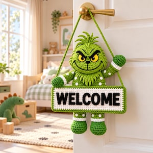 May include: A green crocheted character with yellow eyes, a wide grin, and a tuft of hair on its head, holding a rectangular white sign with the black text WELCOME. The figure is suspended by a green crocheted cord from a gold-colored door handle.