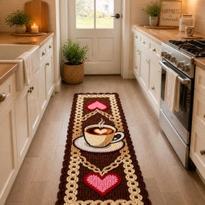 May include: A brown and cream crochet runner rug with a coffee cup and heart design. The rug features a coffee cup with a heart-shaped design in the center, and two pink hearts. The rug is approximately 60 cm wide and 152 cm long.