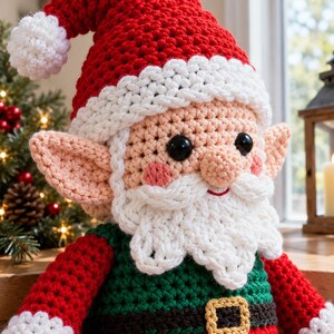 May include: A crocheted Santa Claus doll featuring a red hat with a white pom-pom, large black eyes, a white beard, and pointed ears. The doll wears a green shirt with a black belt and a gold buckle, with red sleeves and white cuffs.