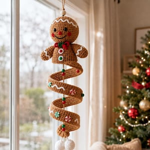 May include: A crocheted gingerbread person hanging ornament with a spiral body. The figure has a brown head, black eyes, a red nose, and a red bow tie. The spiral tail features white wavy lines, red and green beads, and small peppermint candy accents.