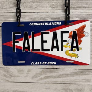 May include: A rectangular license plate with the text "CONGRATULATIONS FALEAFA CLASS OF 2026". The plate has a blue background with a red and white design and a graphic of a bird.