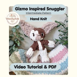 May include: A hand-knit Gizmo-inspired snuggler, featuring a brown and white color scheme with large, textured ears. The plush toy is displayed on a striped blanket with the text "Video Tutorial & PDF". The image also includes the text "Hand Knit".