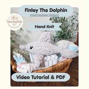 May include: A hand-knit gray dolphin plush toy named "Finley" rests in a wicker basket. The image includes text that reads "Finley The Dolphin", "Intermediate Pattern", "Hand Knit", and "Video Tutorial & PDF". The dolphin is surrounded by other knitted items.