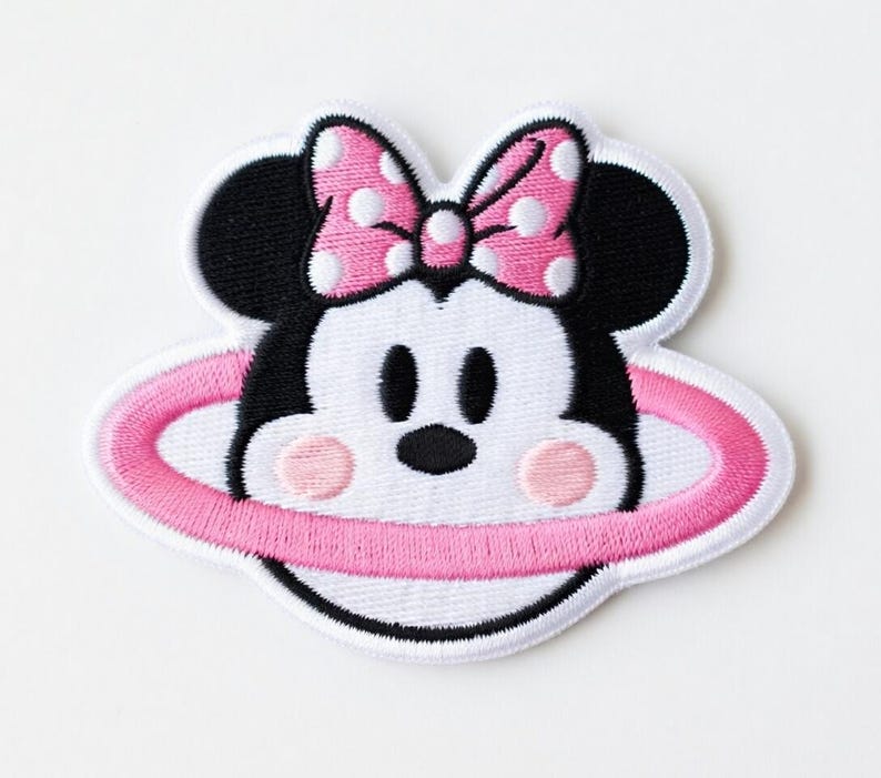 Op de afbeelding: Geborduurde patch met een cartoonmuis met een roze strik en een roze ring rond het gezicht. De muis heeft zwarte oren, ogen en neus, met roze wangen. De patch is wit met zwarte en roze accenten.