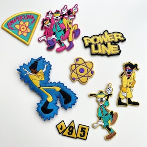 Könnte beinhalten: Eine Sammlung von aufgestickten Aufnähern mit Zeichentrickfiguren und Designs. Enthält Aufnäher mit den Wörtern "POWER LINE" und "95" sowie Charakterillustrationen in leuchtenden Farben wie Gelb, Blau, Rosa und Grün.