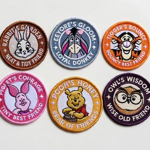 May include: Six embroidered patches featuring characters from Winnie the Pooh. Each circular patch has a different character, including Rabbit, Eeyore, Tigger, Piglet, Pooh, and Owl. Each patch has text related to the character.