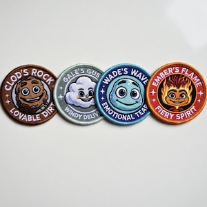 Puede incluir: Cuatro parches bordados circulares con diseños de personajes de dibujos animados. Los parches presentan las frases "Clod's Rock", "Gale's Gus", "Wade's Wave" y "Ember's Flame". Cada parche tiene un diseño y una combinación de colores diferentes, con texto en los bordes.