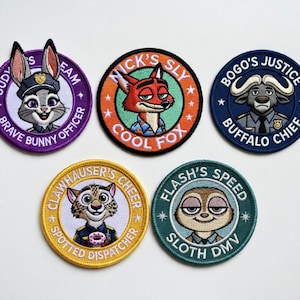 Puede incluir: Parches bordados con personajes de dibujos animados. Los parches son redondos con varios colores y texto. Los personajes incluyen un conejo, un zorro, un búfalo, un guepardo y un perezoso. El texto incluye "Brave Bunny Officer" y "Cool Fox".