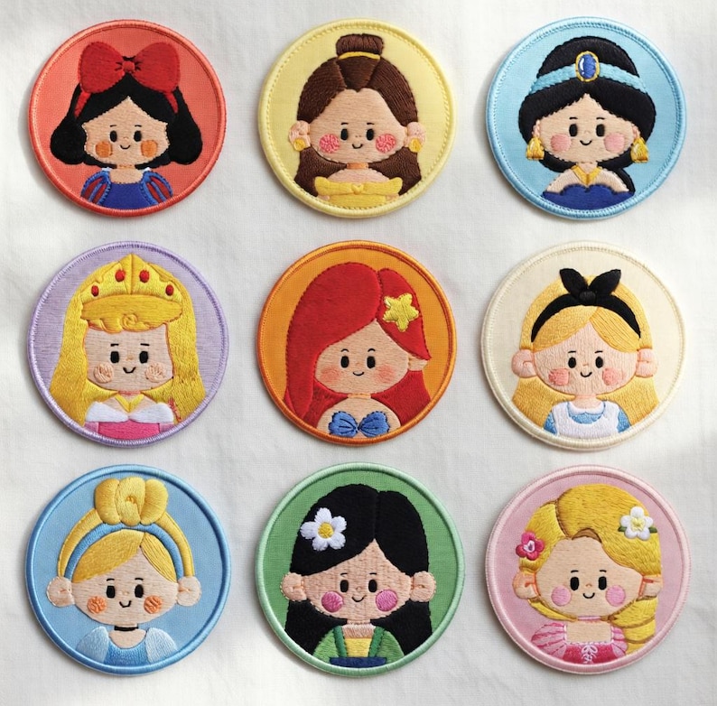 May include: Nine embroidered patches featuring cartoon illustrations of princesses. Each patch is round with a coloured border and depicts a different princess with unique hairstyles and outfits. The patches are colourful and detailed.