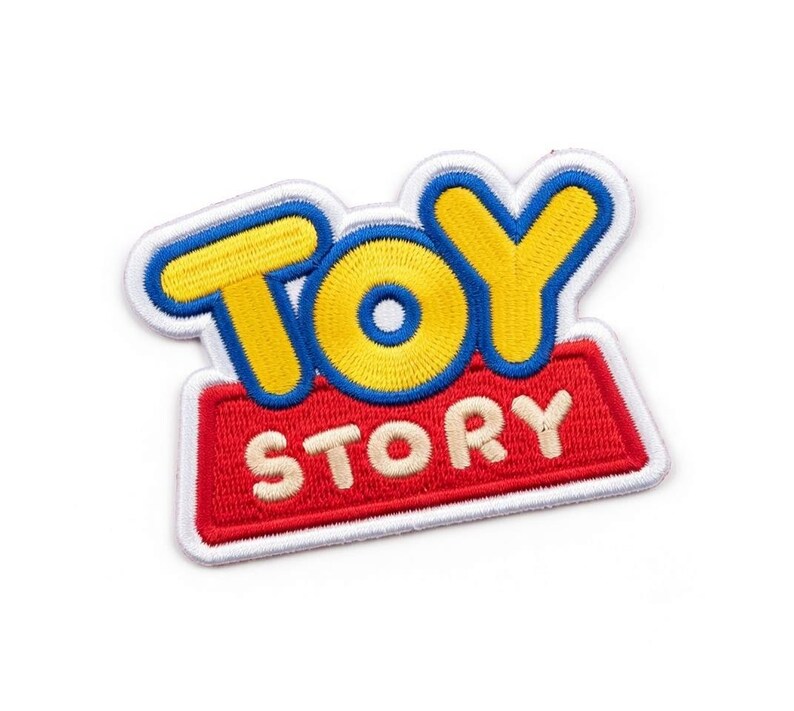 Puede incluir: Parche bordado con el logotipo de "Toy Story". El parche tiene un borde blanco, con las palabras "TOY" en amarillo y azul, y "STORY" en blanco sobre un fondo rojo. El parche est&aacute; dise&ntilde;ado para plancharse.