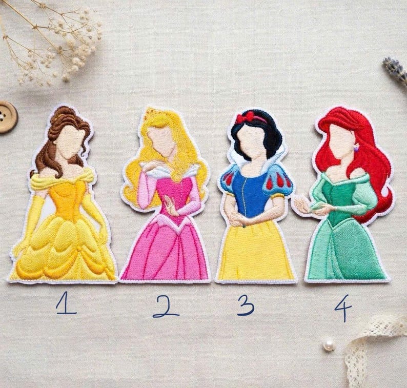 May include: Four embroidered patches featuring cartoon princesses in colorful gowns. Belle in yellow, Aurora in pink, Snow White in blue and yellow, and Ariel in green. Each patch has a white border and a number below.