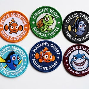 May include: Set of six round embroidered patches featuring characters from a popular animated film. Each patch has a different character and text, including "Nemo's Adventure," "Crush's Wave," and "Bruce's Shark." The patches are in various colors.