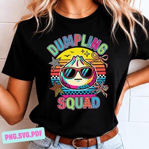May include: Black t-shirt featuring a colorful graphic of a dumpling wearing sunglasses. The text "DUMPLING SQUAD" is arched above the dumpling, with "SQUAD" below. The design includes stars, bows, and a sunset-like background.