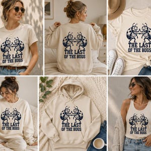 Peut inclure: Une collection de vêtements couleur crème comprenant des t-shirts, des sweat-shirts et un débardeur, chacun arborant un motif bleu foncé de deux coccinelles qui se tapent dans la main avec le texte THE LAST OF THE BUGS imprimé en dessous.