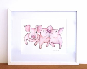 May include: A framed watercolor print featuring three pink pigs. One pig is holding a piece of straw, while the other two are nuzzling. The artwork is set against a white background and framed in a white border.